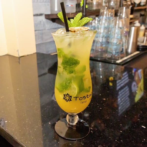 A Tostao's Tapas-bar mojito cocktail with mint and lime on a dark bar counter.