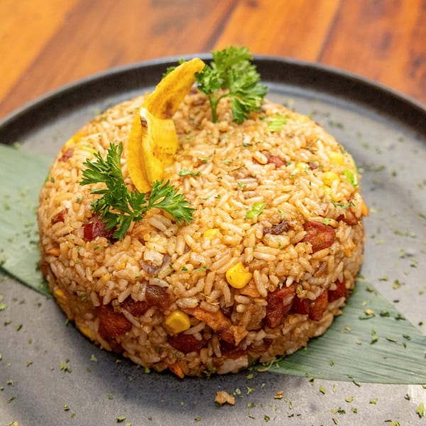 Tostao's Tapas-bar's fried rice with plantain chips and parsley on a dark plate.